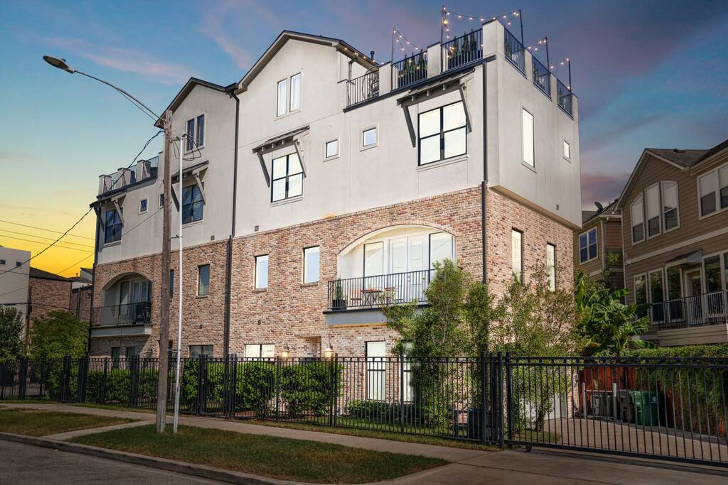 A multi-story residential building with a brick facade, multiple balconies, and a clear sky.