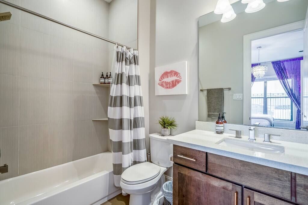 A bathroom with a bathtub, toilet, and vanity with a mirror.