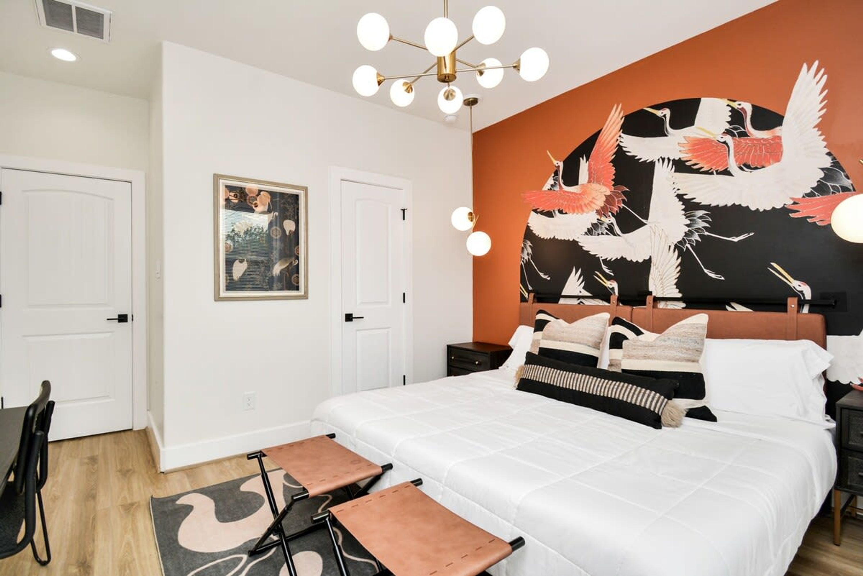 Een slaapkamer met een groot bed, een hoofdbord met muurschildering, een nachtkastje en een nachttafel.