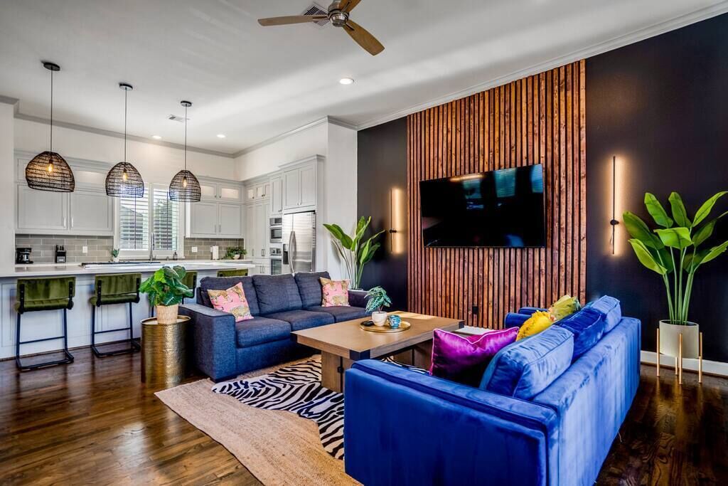 Un salon moderne avec un canapé bleu, un mur d’accent en bois et un téléviseur à écran plat fixé au-dessus.