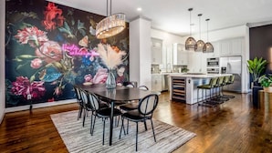 A modern kitchen with white cabinets, a central island, and pendant lighting. - Urban Jungle Retreat in the HTX Skyline (Houston)
