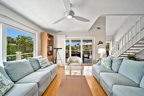 Uma sala de estar ampla com ventilador de teto, uma janela grande e vista para o exterior.