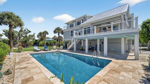 A modern two-story house with a swimming pool, outdoor seating, and a covered patio area.