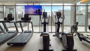 A gym with treadmills, elliptical machines, and a TV screen. - Maison Privee - Modern & Chic Retreat 10min from Downtown Dubai (Dubai)