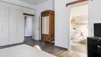 A bedroom with a large bed, a wardrobe, a wooden cabinet, and a TV stand.