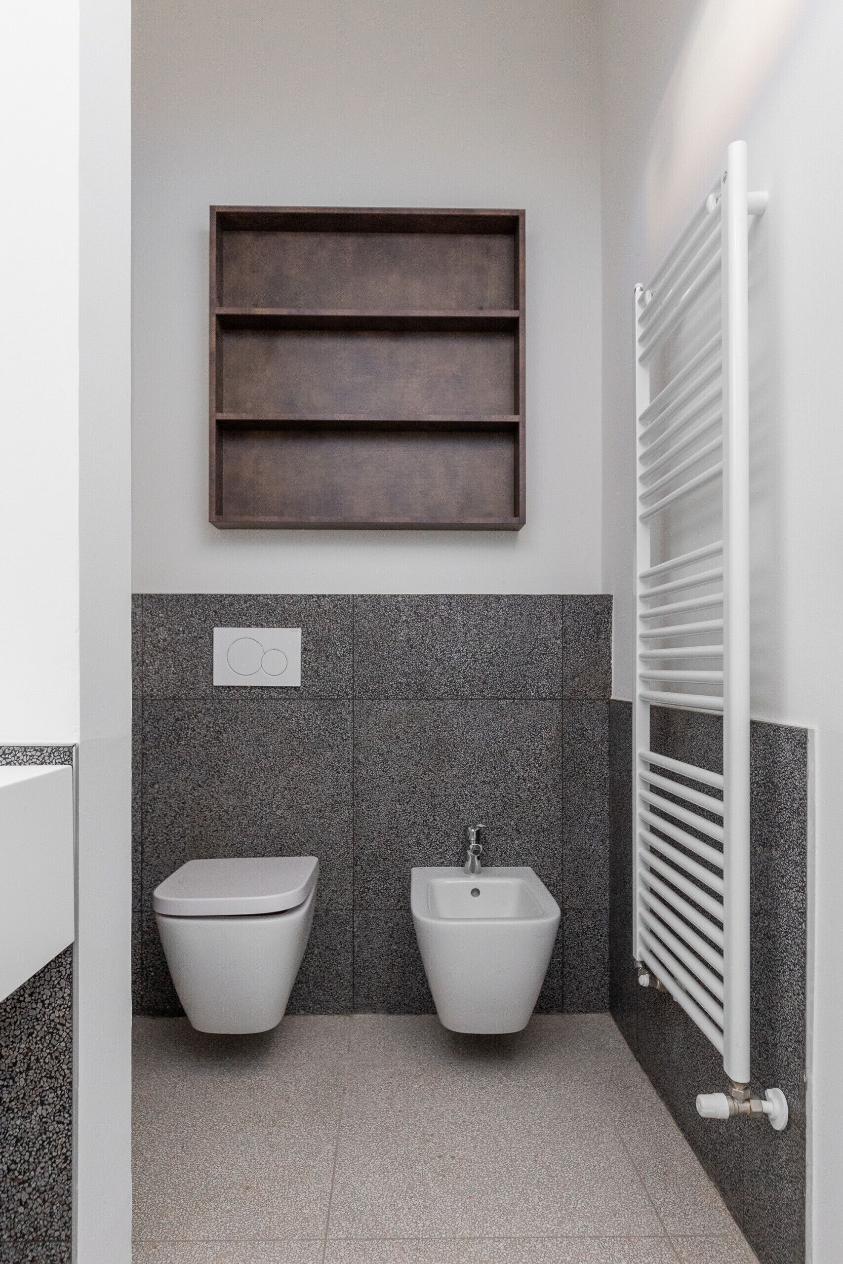 Ein modernes Badezimmer mit Toilette, Bidet und Handtuchhalter.