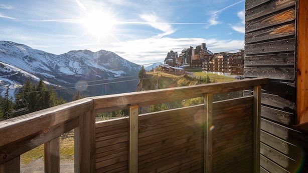 Un balcon en bois offrant une vue sur un paysage montagneux et un bâtiment historique.