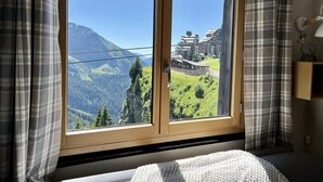 Une pièce dotée d’une grande fenêtre donnant sur une montagne et un bâtiment traditionnel.