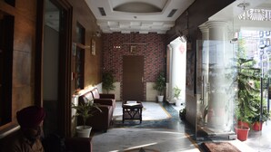 A hotel lobby with a brick wall, a reception desk, seating area, and potted plants.