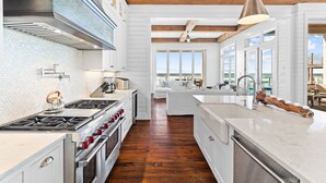 A modern kitchen with white cabinetry, a large island, and a view to the outside. - Gulf Front w/ Pool, LSV and Beach Boardwalk (Santa Rosa Beach)