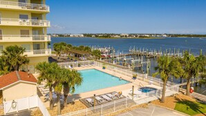 A hotel with a swimming pool, lounge chairs, and a view of the marina.