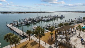 A marina with multiple docks, a wooden walkway, and a covered seating area with palm trees.