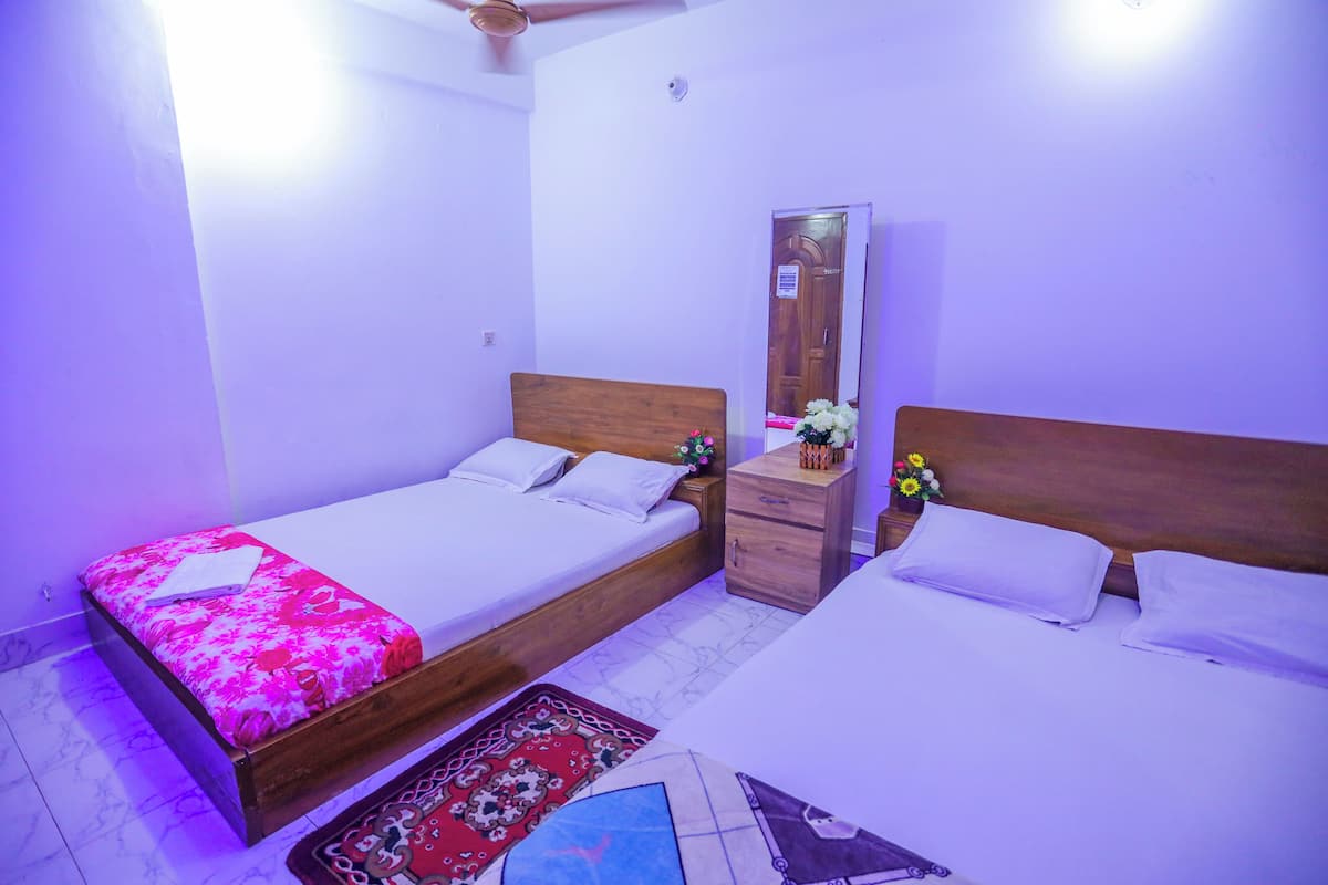 A bedroom with two single beds, a wooden headboard, a nightstand, a mirror, and a floral decoration.