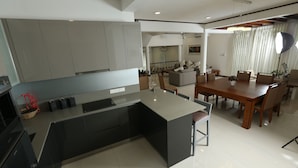 Een moderne keuken met een groot eiland, donkere kasten en een eethoek met een houten tafel en stoelen.