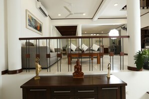 Amplia sala de estar con una mesa de centro de madera, un sofá y una estatua decorativa de Buda.