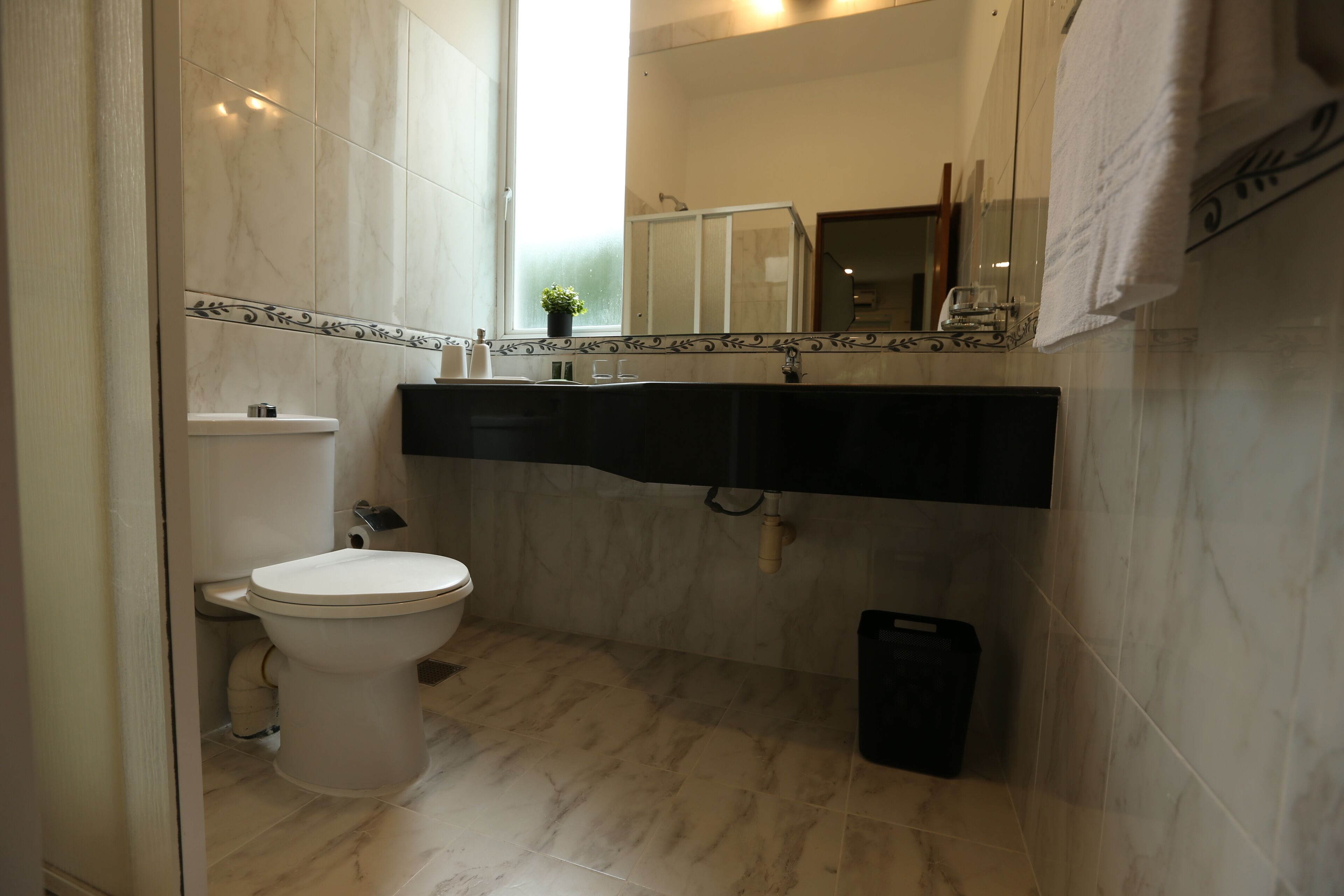 Un baño con inodoro, lavamanos y espejo.