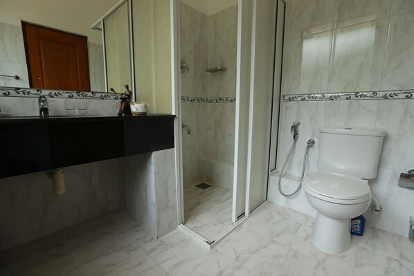 Un baño con cabina de ducha, inodoro y lavamanos con encimera negra.