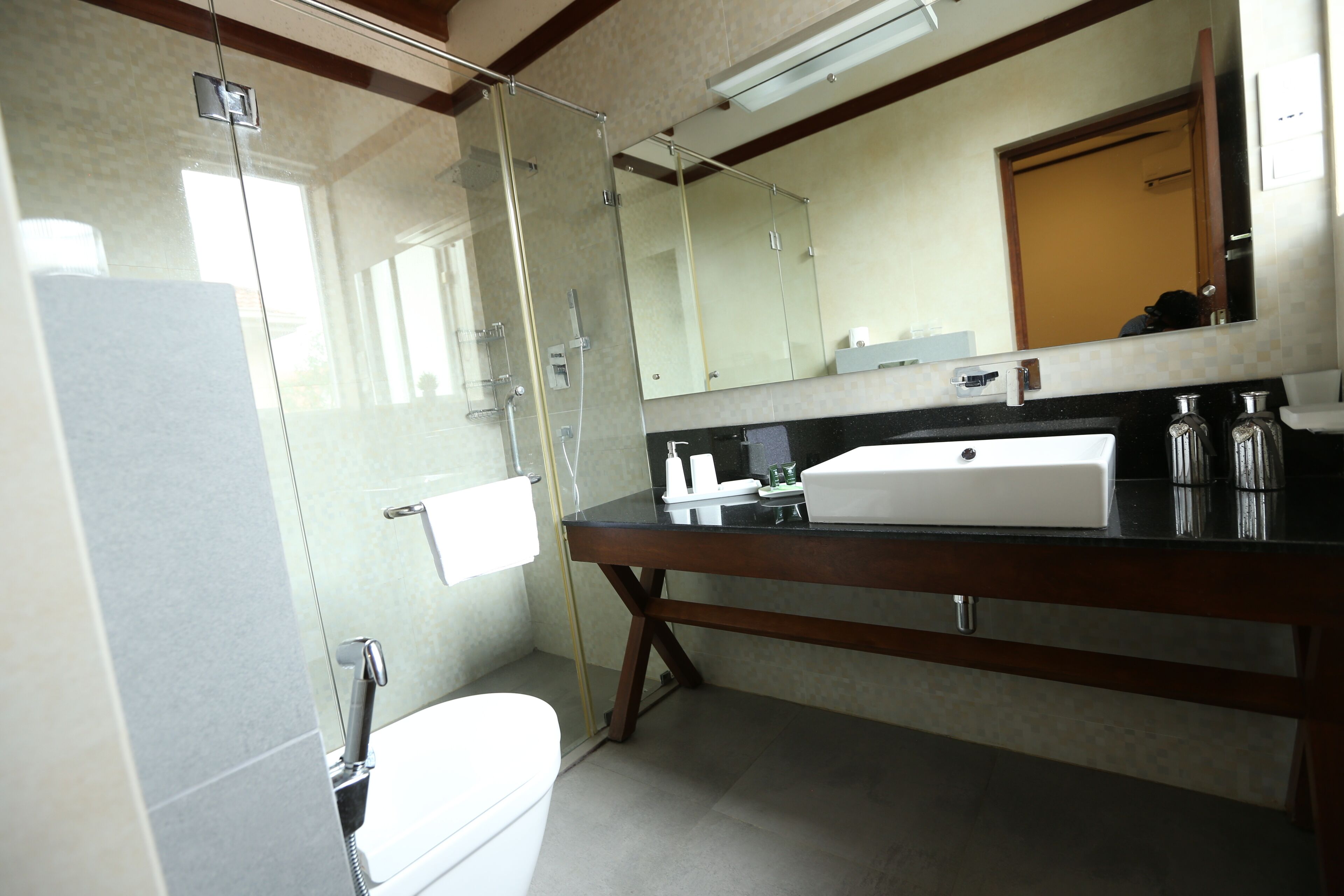 A bathroom with a glass-enclosed shower, a white toilet, a black countertop with a sink, and a mirror above the sink.