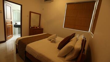 Quarto de hotel com cama, penteadeira, espelho e janela com persianas.