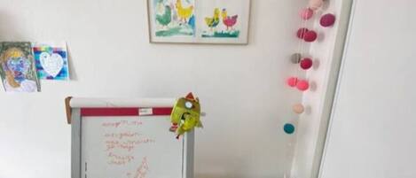 A classroom with a whiteboard, children's drawings, and educational toys.