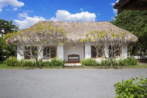 A house with a thatched roof, white walls, and a bench in front. - Casa Encantos Beach Front House (Hacienda Iguana)