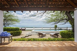 A pool area with a view of the sea, surrounded by greenery and a pergola. - Casa Encantos Beach Front House (Hacienda Iguana)