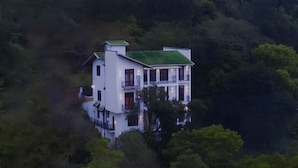 Un immeuble à plusieurs étages doté d’un toit végétalisé, entouré d’une forêt dense.