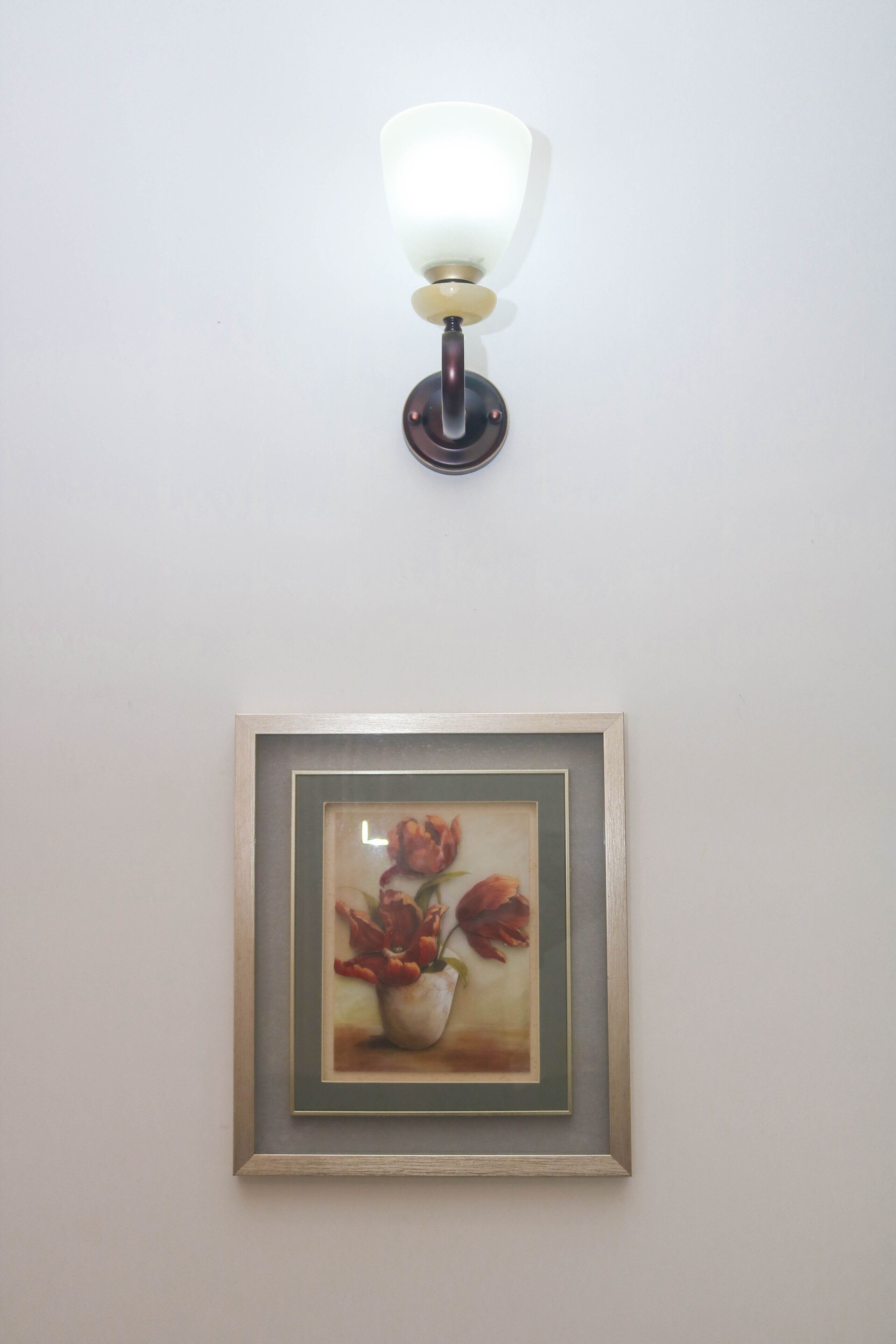 A wall-mounted light fixture above a framed artwork.