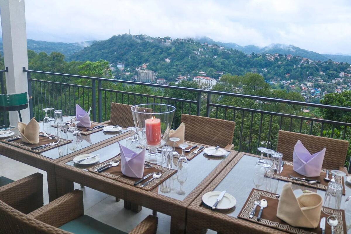 A dining table set with glassware, plates, and napkins, overlooking a mountainous landscape.