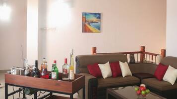 A living room with a wooden ceiling, a sofa set, a coffee table, and a cart with bottles and glasses.