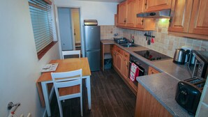 Una cocina compacta con armarios de madera, un refrigerador de acero inoxidable, un horno empotrado y un tostador.