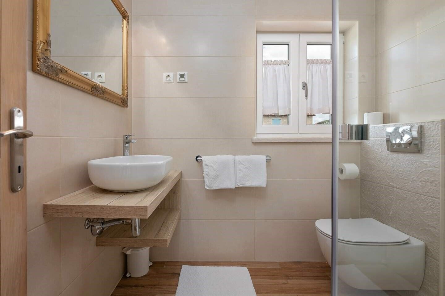 A modern bathroom with a wooden vanity, a large mirror, a toilet, and a shower area.