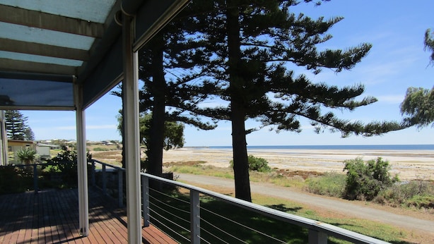 A wooden deck with a railing overlooking a beach and ocean.