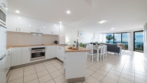 Una cucina moderna con mobili bianchi, forno integrato e zona pranzo con tavolo e sedie.