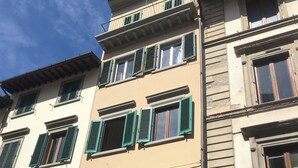 A multi-story building with green shutters, a visible storefront with signage, and a clear sky. - Borgo Ognissanti Suites Stay in the Heart of Florence! 🔝 brand new location (Firenze)