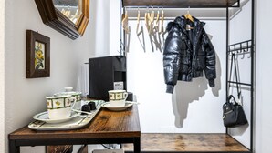A room with a wooden table displaying tea sets, a coat rack with a jacket, and a mirror on the wall. - Borgo Ognissanti Suites Stay in the Heart of Florence! 🔝 brand new location (Firenze)