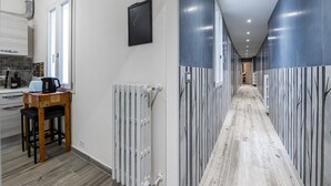 A hallway with a wooden floor, white walls, and a radiator. There is a wooden stool with a kettle on it. - Borgo Ognissanti Suites Stay in the Heart of Florence! 🔝 brand new location (Firenze)