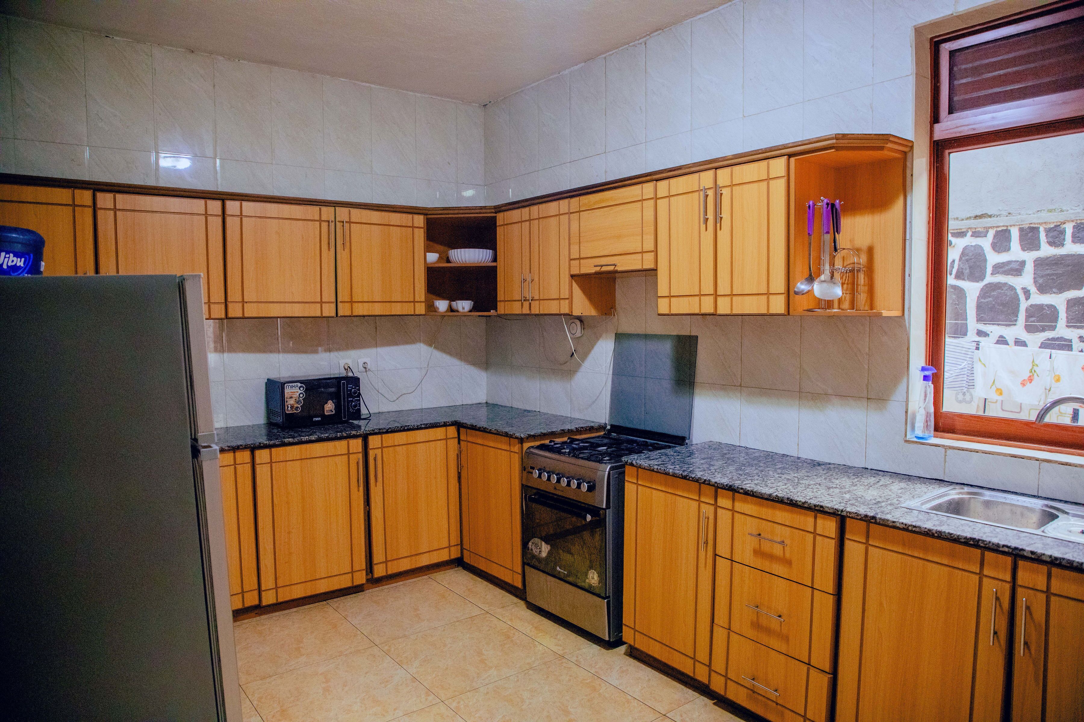 Une cuisine avec des meubles de rangement en bois, une cuisinière et un four à micro-ondes.