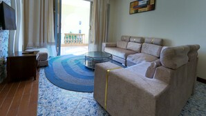 A living room with a beige sofa, a glass coffee table, and a patterned rug. - Magical Beachfront Apartments (Mombasa)