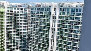 Un hotel moderno con múltiples balcones, un área de piscina con palmeras y una playa.