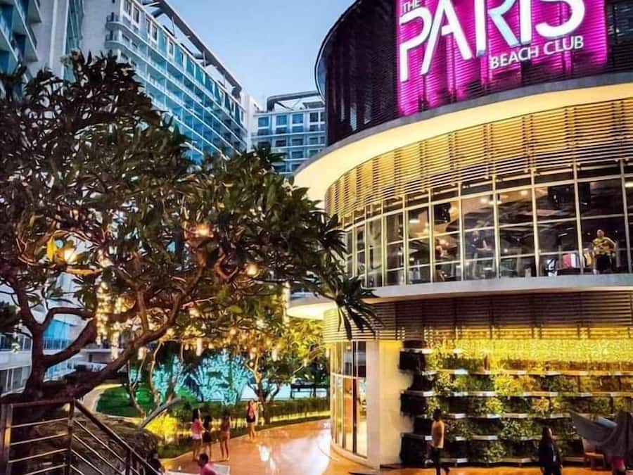 The Paris Beach Club with a modern glass facade, outdoor seating area, and a visible pool.