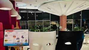 Un interior moderno con una gran instalación escultórica blanco y negro, una zona de estar roja y un letrero.