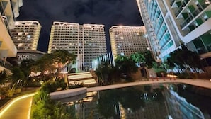Vista nocturna de un edificio de gran altura con una piscina al frente.