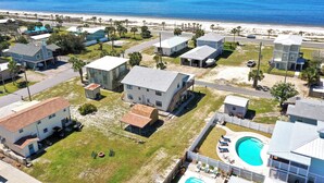 Un quartier résidentiel avec des maisons, une piscine et une plage en arrière-plan.