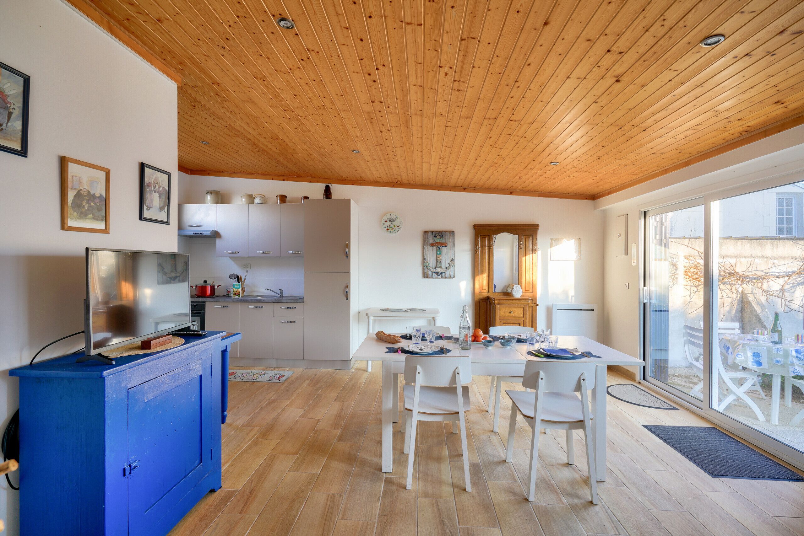 Une cuisine moderne avec des meubles blancs, un plan de travail bleu et un coin repas avec des chaises blanches.