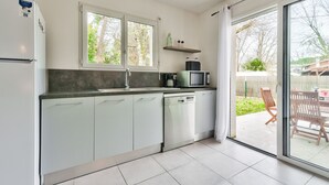 A modern kitchen with white cabinets, a dishwasher, a microwave, and a window above the sink. - House for 6 -Pool - 150m from the beach in Arès (Arès)