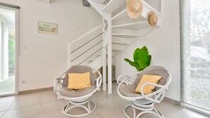 A modern interior with a white spiral staircase, two wicker chairs with cushions, a large green plant, and a framed picture on the wall. - House for 6 -Pool - 150m from the beach in Arès (Arès)