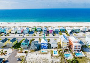 A coastal residential area with colorful houses, a beach, and a clear view of the ocean.