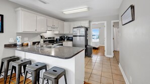 A modern kitchen with white cabinets, a granite countertop, and a stainless steel refrigerator.