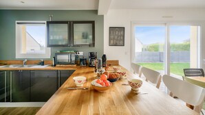 A modern kitchen with a wooden countertop, stainless steel appliances, and a large window overlooking a backyard. - House with pool for 8 - 500m from the beach (Plobannalec-Lesconil)